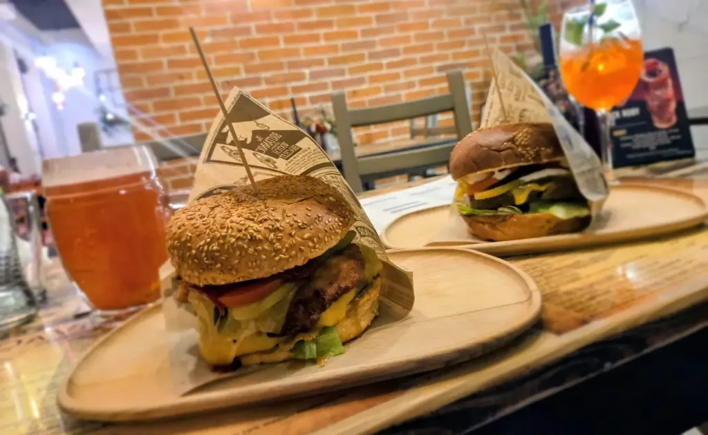 Dwa burgery Da Vinci podane na drewnianych talerzach